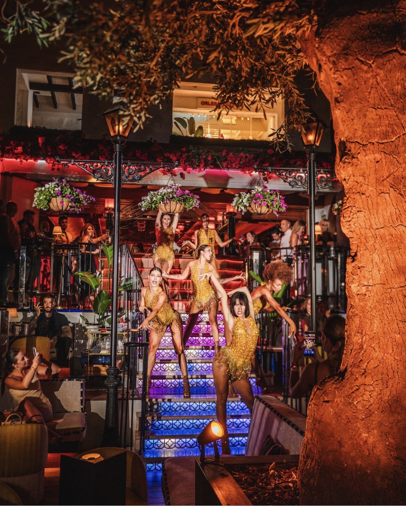 Dancers in gold costumes performing on the lit staircase at La Plaza, Puente Romano