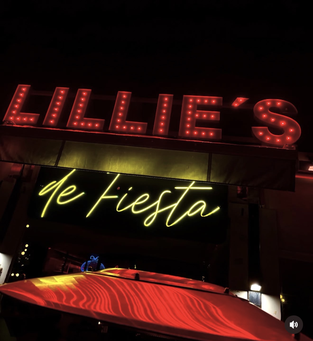 Red neon 'Lillie's' marquee sign lit up above the terrace entrance at night
