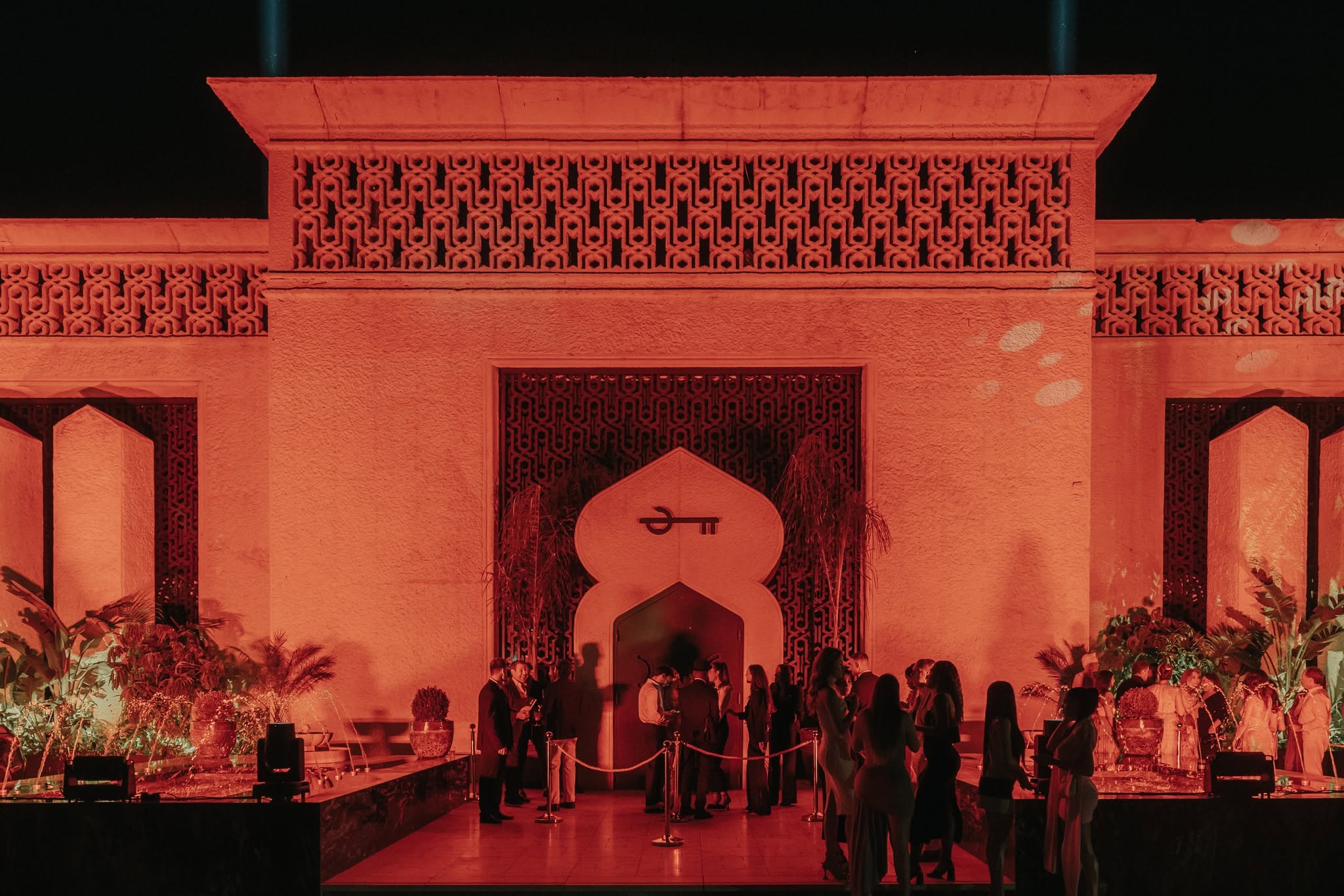 Guests behind the rope at the keyhole-arch entrance to Motel Particulier Marbella, floodlit red at night