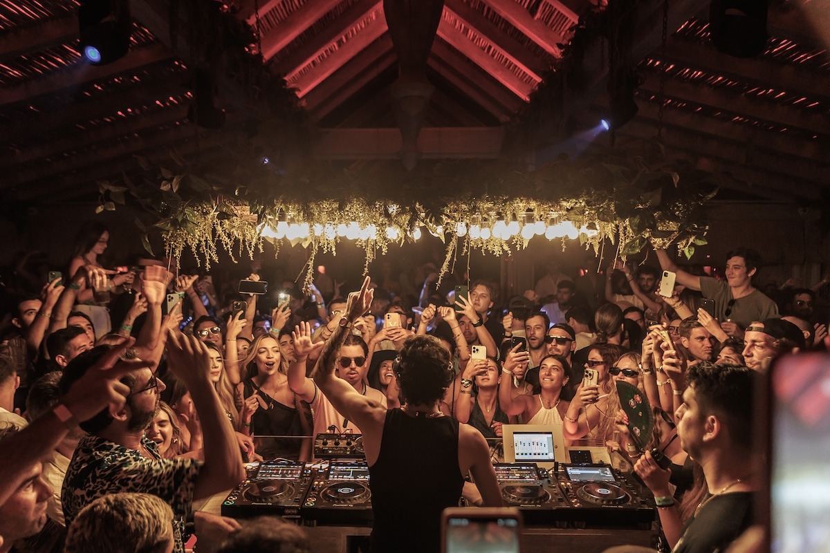 DJ playing to a packed crowd under the thatched roof at Playa Padre beach club, Marbella